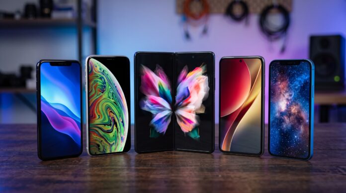 Varios smartphones modernos, incluido un plegable, acomodados en abanico sobre un escritorio